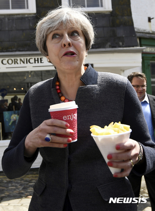 【메바기시=AP/뉴시스】테리사 메이 영국 총리가 2일(현지시간) 콘웰 메바기시에서 선거 유세를 진행하던 중 감자튀김을 먹고 있다. 2017.5.3.