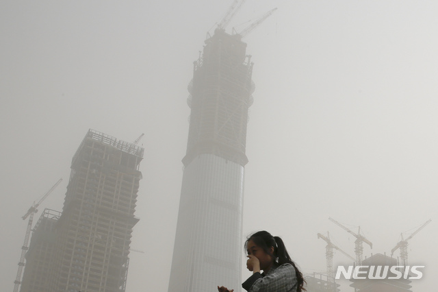 A woman covers her face by hands from polluted air and sandstorm in Beijing, Thursday, May 4, 2017. Authorities in Beijing issued a blue alert on air pollution as sandstorm swept through the Chinese capital city on Thursday morning. (AP Photo/Andy Wong)