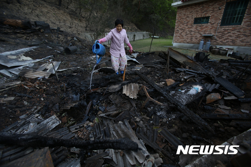 【강릉=뉴시스】김경목 기자 = 7일 전날 강원 강릉시 성산면 어흘리에서 시작된 산불로 집에 불에 타 재산피해를 입은 이재민 김옥년(76) 할머니가 내려 앉은 집 잿더미에서 불이 올라오자 겁이 나 물을 뿌려 끄느라 힘들어하고 있다. 남편과 함께 사는 김 할머니내 댁은 다행히 인명피해는 없었다. 2017.05.07.&nbsp; photo31@newsis.com