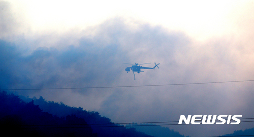 【강릉=뉴시스】김경목 기자 = 7일 산림청 산불 진화 헬기가 강원 강릉시 성산면 일대에서 발생한 산불을 끄기 위해 대량의 물을 싣고 연기를 뚫고 투하 지점으로 비행하고 있다. 2017.05.07. photo31@newsis.com