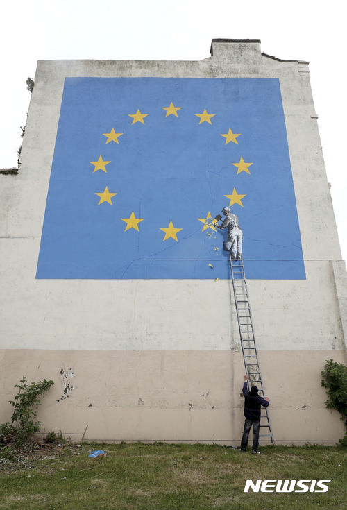 【도버=AP/뉴시스】한 남성이 8일(현지시간) 항구도시 도버에서 뱅크시의 벽화 옆에서 인증샷을 찍고 있다. 전날 등장한 이 벽화에는 한 인부가 유럽연합(EU) 깃발에 있는 별 12개 중 1개를 지우는 모습이 담겨 영국의 EU 탈퇴를 묘사한 것으로 보인다. 2017.05.09&nbsp; 