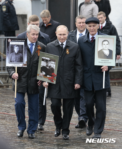 【모스크바=AP/뉴시스】블라디미르 푸틴 러시아 대통령(가운데)이 9일(현지시간) 전승절을 맞아 러시아 모스크바에서 열리는 ‘불사조 연대(Immortal Regiment)’ 행사에 참석하기 위해 친부 사진을 들고 있다. 이 행사에서는 수많은 시민이 트베르스카야 거리에서 2차 세계대전에서 고통을 당한 가족의 사진을 들고서 구경했다. 2017.05.10
