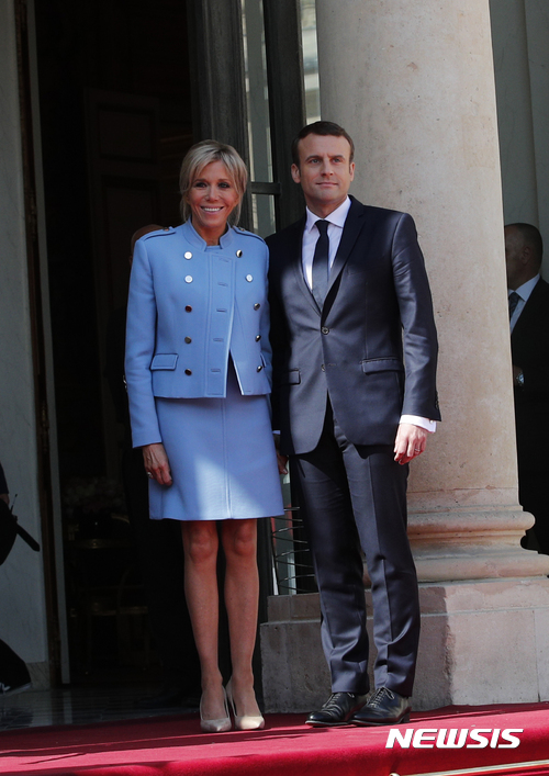 【파리=AP/뉴시스】에마뉘엘 마크롱 신임 프랑스 대통령과 부인 브리지트 여사가 14일(현지시간) 파리 엘리제궁 앞에서 포즈를 취하고 있다. 브리지트 여사가 입은 하늘색 투피스는 루이 비통 제품이다. 2017.05.15 