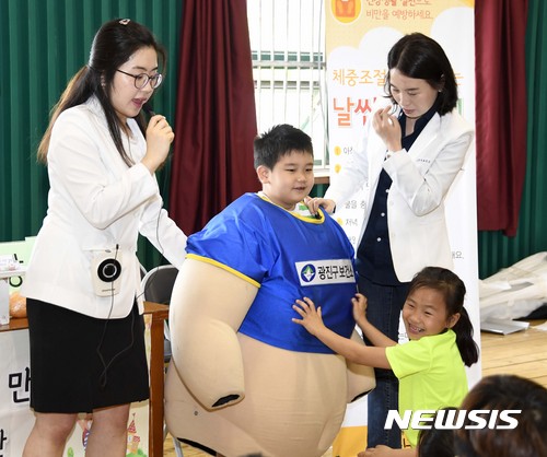 【서울=뉴시스】22일 서울 광진구 장안초등학교에서 열린 건강한 학교만들기 청소년 이동 건강체험·홍보관 '영양·비만관'에 참가한 학생이 비만조끼를 입고 가상비만체험을 하고 있다. 2017.05.22. (사진=광진구 제공) photo@newsis.com