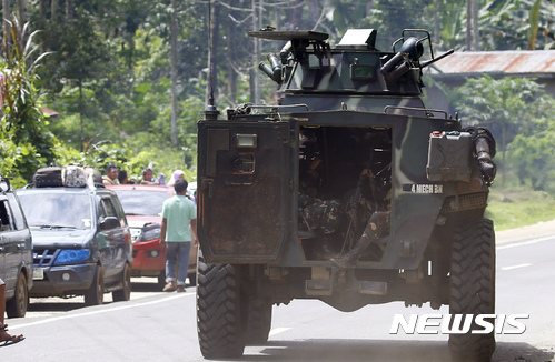 【마라위(필리핀)=AP/뉴시스】필리핀 남부 민다나오섬 마라위를 이슬람국가(IS) 연계 마우테 반군으로부터 탈환하려는 필리핀 정부군과 반군 간에 치열한 전투가 계속되는 가운데 29일 마라위를 빠져나가려는 시민들의 자동차 행렬 옆으로&nbsp; 정부군 장갑차 한 대가 지나가고 있다. 2019.5.29