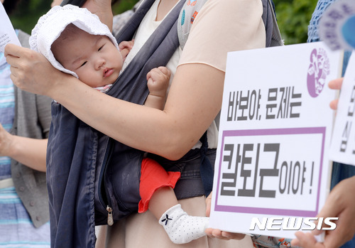 【서울=뉴시스】배훈식 기자 = 21일 오전 서울 여의도 국회 정문 앞에서 '정치하는 엄마들' 기자회견에 참석한 한 회원의 아기가 칼퇴근법 통과를 촉구하는 피켓을 바라보고 있다. 2017.06.21. dahora83@newsis.com