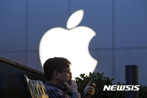 FILE - In this Friday, May 13, 2016, file photo, a man uses his mobile phone near an Apple store in Beijing. On Wednesday, July 12, 2017, Apple announced it will open a data center in mainland China with ties to the country’s government, raising concerns about the security of iCloud accounts that store personal information transferred from iPhones, iPads and Mac computers there. (AP Photo/Ng Han Guan, File)