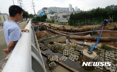 【청주=뉴시스】2017년 7월 17일 충북 청주시 흥덕구 향정동 서청주교 사거리 일대에서 시민들이 폭우로 파열된 상·하수관을 바라보고 있다. (사진= 뉴시스 DB)