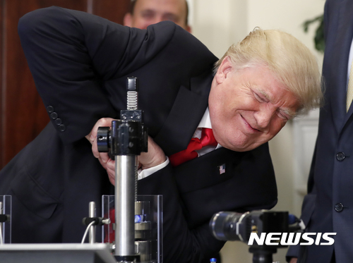 【 워싱턴=AP/뉴시스】도널드 트럼프 미국 대통령이 20일(현지시간) 워싱턴 로즈벨트룸에서 머크,파이저,코닝사가 합작해 약 보관용으로 새로 개발한 초강력 유리병을 부수려고 안간힘을 쓰고 있다. 트럼프 대통령은 약 1000파운드(약454kg)의 무게를 가했지만, 유리병을 깨는데 실패했다. 2017.07.21