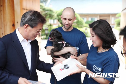【서울=뉴시스】전신 기자 = 문재인 대통령이 26일 청와대 관저 앞에서 동물권단체 '케어'로부터 유기견 '토리'의 그림이 그려진 액자를 전달받고 있다. 문 대통령은 "이제는 반려동물을 키우는 사람들이 천만을 넘어선 시대가 됐다. 사람과 반려동물이 공존하면서 함께 행복할 수 있는 사회가 되어야 할 것이다. 해마다 백만마리 정도가 새 주인을 찾아가는데 그 중 또 삼십만 마리가 버려지는 것이 현실이기도 하다. 이제는 유기동물에게도 사회 전체가 돌봐주고 관심을 가져야 할 것이다"라고 말했다. 2017.07.26. (사진=청와대 제공) photo@newsis.com
