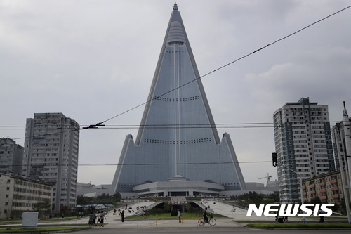 【평양=AP/뉴시스】북한이 대륙간탄도미사일 2차 시험발사 성공을 대대적으로 선전한 것과 달리 세계에서 가장 큰 호텔 류경호텔 주변을 개축해 조용히 공개했다. 105층짜리 류경호텔 주변 건축 현장에서 보행자 보호용 차단벽이 전승일인 지난 27일 철거됐다. 북한 주민들은 지난 28일 평양에 있는 류경호텔을 지나가는 모습. 20.17.07.31