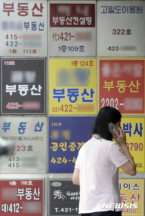 【서울=뉴시스】최동준 기자 = 정부가 서울 전역과 과천시를 투기과열지구로 지정하고 강남 4구를 포함한 서울 11구, 세종시를 투기지역으로 지정하는 고강도 대책을 내놓았다. 2일 한 시민이 서울 시내 부동산 중개업소 간판 앞을 지나고 있다. 2017.08.02. photocdj@newsis.com
