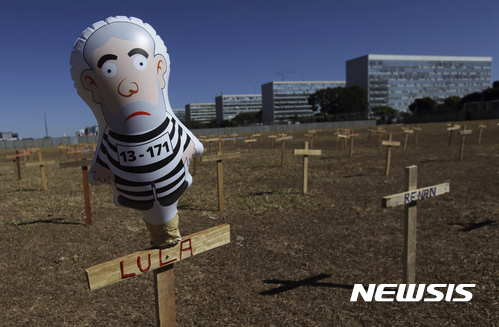 【브라질리아( 브라질 = AP/뉴시스】 = 브라질리아의 반부패 시위대들이 부패정치인의 이름을 새겨 마련한 가짜 공동묘지 앞에 루이스 이나시우 룰라 다 시우바의 죄수복 차림 인형이 전시되어 있다. 불황과 정치 부패, 최악의 인플레이션으로 몸살을 앓고 있는 브라질 정부는 4개 수력발전댐의 운영권을 경매를 통해 외국 회사에 매각하고 석유 시추와 채굴 사업도 외국 회사 컨소시엄에 팔아 넘겼다.