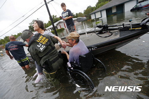 【댈라스( 미 텍사스주) = AP/뉴시스】 = 하비로 인한 홍수로 물에 잠긴 텍사스주 오렌지의 주택가에서 구조요원들이 한 여성을 대피시키고 있다.