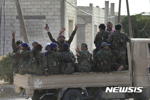 【락까=AP/뉴시스】미군이 지원하는 쿠르드족과 아랍계 민병대 '시리아민주군(SDF)이 소속 데이르 에즈 조르 군사위원회(DEMC)는 9일(현지시간) 동부 데이르 에즈 조르에서 탈환전을 개시했다. 사진은 SDF 군인들이 지난 7월22일 시리아 북동부 락까에서 이슬람 극단주의 무장단체 IS과 싸우기 위해 최전방으로 이동하기 위해 트럭을 타고 지나가는 모습. 2017.09.10.