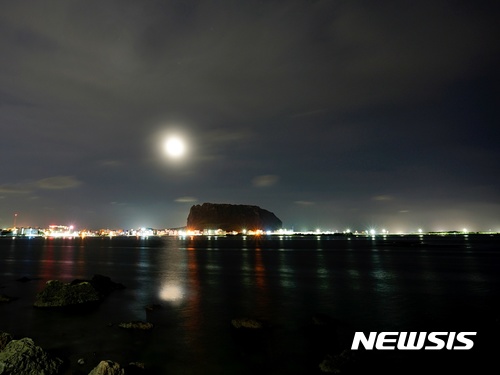 【제주=뉴시스】제주 서귀포시 성산읍 성산일출봉 위로 달이 떠오르는 모습. 바다 위에 은은히 비치는 달빛이 아름답다. (사진=제주관광공사 제공) photo@newsis.com