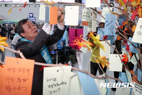 【서울=뉴시스】 도종환 문화체육관광부장관이 추석 연휴를 하루 앞둔 29일 서울역에서 열린 2018평창동계올림픽대회 홍보행사에 참석해 올림픽 성공기원 메시지를 행운의 나무에 걸고 있다. 2017.09.29. (사진=문화체육관광부 제공) photo@newsis.com