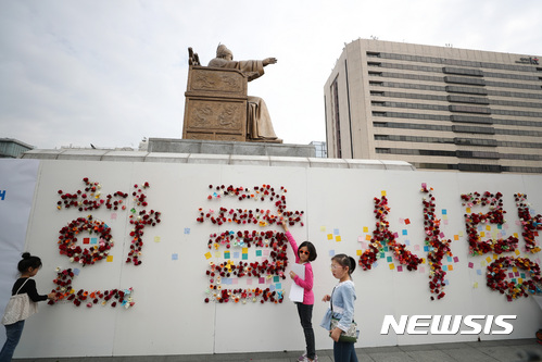 【서울=뉴시스】김진아 기자 = 571돌 한글날인 9일 서울 종로구 광화문광장 세종대왕 동상에 설치된 571돌 한글날 시민 꽃 바치기 조형물에서 시민들이 꽃을 꽂으며 사진을 찍고 있다. 2017.10.09. bluesoda@newsis.com