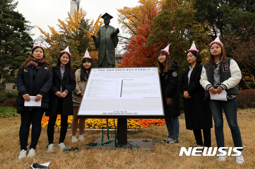 【서울=뉴시스】박주성 기자 = 이화여대 친일청산 프로젝트 기획단 학생들이 13일 오후 서울 서대문구 이화여대 본관 옆 김활란 동상 앞에서 김활란 친일행적 알림팻말 제막식을 하고 있다. 올해 3월부터 시작된 프로젝트는 김활란의 친일행적을 알리고 친일파의 동상이 대학 교정에 존재하는 현실을 바로잡기 위해 1022명의 학생들이 팻말 제작을 완료했다. 2017.11.13. park7691@newsis.com