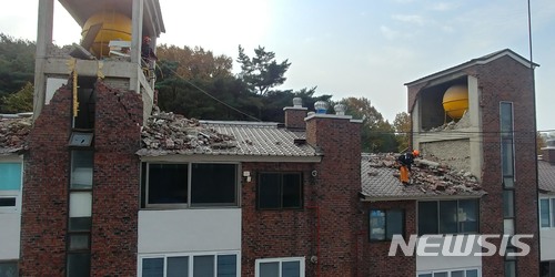 【부산=뉴시스】 하경민 기자 = 부산소방안전본부는 지난 20일부터 특수구조대 1개팀 6명으로 구성된 안전조치반을 포항지진 현장에 긴급 파견했다고 22일 밝혔다.사진은 포항시 북구의 한 빌라에서 구조대원들이 로프에 의지해 낙하위험물을 제거하고 있는 모습. 2017.11.22. (사진=부산소방본부 제공)yulnetphoto@newsis.com