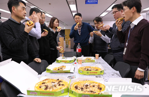 【세종=뉴시스】지난해 문재인 대통령이 보낸 피자를 나눠 먹고 있는 기획재정부 공무원의 모습. 문 대통령은 올해 떡 1300개를 보내 예산안 준비로 격무에 시달려 온 기재부 공무원들에게 고마움을 표시했다. (사진=뉴시스DB).2017.12.06.