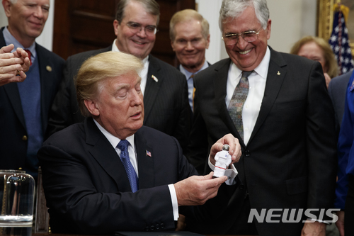 【워싱턴=AP/뉴시스】도널드 트럼프 미국 대통령이 11일(현지시간) 백악관에서 달 유인탐사 재개 행정지침에 서명한 후 아폴로 17호 조종사였던 잭 슈미트로부터 우주인 인형을 선물받고 있다.&nbsp; 2017.12.12