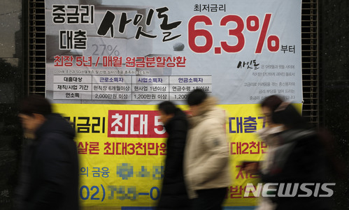【서울=뉴시스】최동준 기자 = 시민들이 서울 시내 한 금융기관 대출 광고 현수막 앞을 지나가고 있다. 한국은행에 따르면 금리가 오르면 가계빚을 보유한 차주 중에서도 '저소득층', '50대', '자영업자'가 큰 타격을 입을 것이라는 분석이 나왔다. 2017.12.14. photocdj@newsis.com