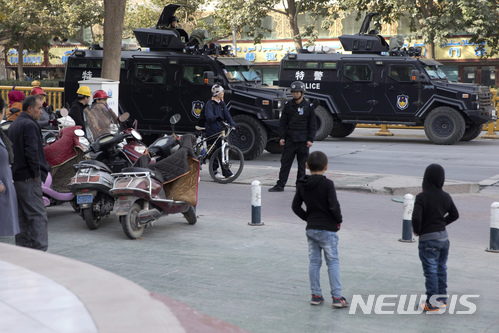 【카시가르(중국 신장위구르자치구)=AP/뉴시스】지난 11월5일 중국 신장(新疆)위구르자치구의 카시가르에서 주민들이 시내에 배치된 경찰 장갑차들을 지켜보고 있다. 신장위구르자치구에서는 지난해부터 수만명이 실종됐다. 이들은 중국이 이념 주입을 위해 운용하는 비밀수용소에 재판도 없이 넘겨진 것으로 추측되지만 아무도실제로 어떤 일이 있어났는지는 알지 못한다. 신장위구르 지역은 경찰의 치밀한 감시 속에 공포의 경찰국가로 변모하고 있다. 2017.12.17 