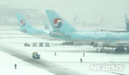 【인천공항=뉴시스】홍찬선 기자 = 18일 오전 중부지방에 내린 폭설로 인해 인천국제공항에 여객기 지연이 속출하고 있다. 이날 눈 내리는 인천공항 계류장에서 관계자들이 분주하게 움직이고 있다. 이날 폭설로 인해 인천공항은 출발 41편, 도착 12편이 지연됐고, 김포공항도 국내선 20편이 지연, 6편이 결항 됐다고 밝혔다. 2017.12.18. mania@newsis.com