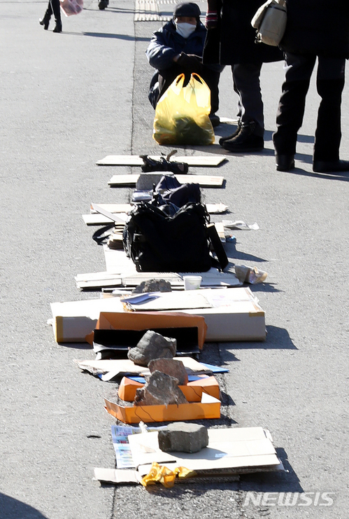 【서울=뉴시스】이종철 기자 = 서울 날씨가 영하 11도의 강추위를 보인 27일 오전 서울역 광장에서 노숙인들이 추위 때문에 점심 배식줄을 서는 대신 돌과 박스로 줄을 만들어 두고 있다. 2017.12.27. jc4321@newsis.com
