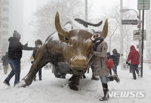【뉴욕=AP/뉴시스】다우 지수가 사상 처음으로 2만5000선을 돌파한 4일 뉴욕 맨해튼 월스트리트의 황소상(Charging Bull) 앞에서 한 여성이 눈이 내리는 가운데 포즈를 취하고 있다. 도널드 트럼프 미 대통령은 4일 기자들에게 "다음 목표는 3만"이라고 말했다. 2018.1.5