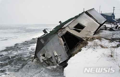 FILE - In this Dec. 8, 2006, file photo, Nathan Weyiouanna's abandoned house at the west end of Shishmaref, Alaska, sits on the beach after sliding off during a fall storm in 2005. Alaska health officials are warning that serious health issues could crop up as the state warms. A report by the Alaska Division of Public Health released this week says longer growing seasons and fewer deaths from exposure are likely positive outcomes from climate change. But the 77-page report says additional diseases, lower air quality from more wildfires, melting permafrost and disturbances to local food sources also are potential outcomes. Warming already has thawed soil and eroded coastlines, leading at least three villages, Shishmaref, Kivalina and Newtok to consider relocating. (AP Photo/Diana Haecker, File)