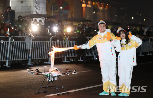 【서울=뉴시스】김진아 기자 = 13일 오후 서울 종로구 광화문 일대에서 2018 평창동계올림픽 성화 봉송 행사에서 KT 신입사원들이 드론에 붙은 성화봉에 토치키스 하고 있다. 2018.01.13.&nbsp; bluesoda@newsis.com