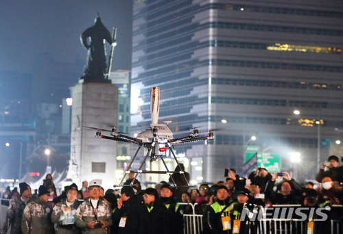 【서울=뉴시스】KT(회장 황창규, www.kt.com)는 13일 밤 서울 종로구 광화문광장에서 2018 평창동계올림픽 대회의 성공 개최를 기원하는 ‘스페셜 성화봉송’ 행사를 진행했다고 밝혔다. 이번 세계 최초 5G 기반의 성화봉송은 과거와 현재, 그리고 미래를 5G 기술로 연결했다는 점이 주목할 만하다. 문화올림픽 대표 도시로 선정된 서울시와 평창동계올림픽 조직위원회, 성화봉송 프리젠팅 파트너인 KT가 공동 주관했다.&nbsp; 광화문광장에서 5G드론이 성화를 봉송하고 있다. 2018.01.14. (사진=KT 제공) photo@newsis.com