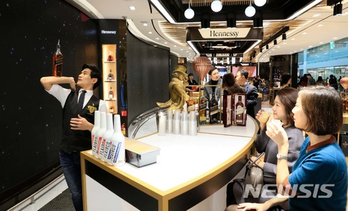 【서울=뉴시스】 18일 인천공항 제2여객터미널에 오픈한 롯데면세점을 찾은 고객들이 주류·담배 플래그십 매장에서 전문 바텐더의 공연을 보며 칵테일 시음을 하고 있다. (사진=롯데면세점 제공) 