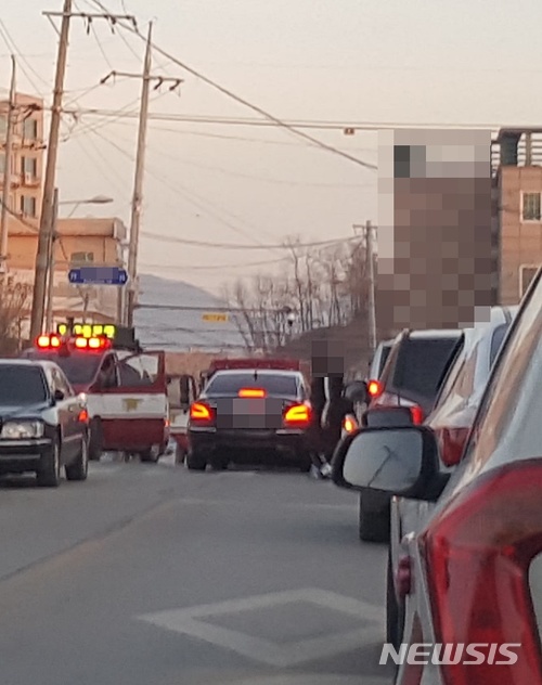 【제천=뉴시스】강신욱 기자 = 19일 오후 5시3분께 충북 제천의 한 학교에서 화재 신고를 받고 출동한 제천소방서 소방차량이 교문이 굳게 잠겨 진입하지 못한 채 대기하고 있는 가운데 한 승용차가 소방차 앞을 지나고 있다.. 이곳 주변 도로 양쪽에는 여전히 불법 주·정차 차량으로 가득하다. 2018.01.19. (사진=독자 제공) photo@newsis.com