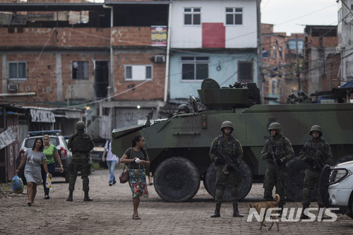 【리우데자네이루(브라질)=AP/뉴시스】브라질 리우데자네이루의 빈민가 켈슨 지구에서 브라질 해병대가 장갑차 옆에서 경계를 서고 있다. 미셰우 테레르 브라질 대통령은 지난 16일 리우데자네이루의 폭력 급증 해결을 위해 군을 투입하는 포고령을 발표했다. 브라질 하원은 20일 테메르 대통령의 군투입 포고령을 승인했다. 2018.2.21