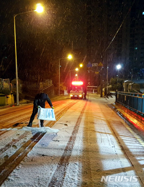 【부산=뉴시스】 하경민 기자 = 부산경찰청은 21일 부산 고지대에 진눈깨비가 내리는 바람에 총 8곳의 도로를 통제 중이라고 밝혔다. 사진은 눈 때문에 통제된 부산진구 부암동의 오르막길에서 관계자가 염화칼슘을 뿌리고 있다. 2018.03.21. (사진=부산경찰청 제공) yulnetphoto@newsis.com 
