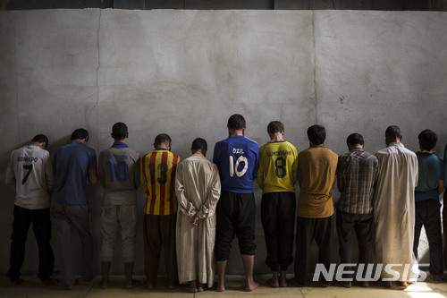 【디비스(이라크)=AP/뉴시스】이라크 디비스에서 2017년 10월3일 이슬람국가(IS)에 연계됐다는 혐의를 받고 있는 하위자 출신 남성들이 교도소에 서 벽을 보고 도열해 있다. 이라크는 최소 1만9000명을 IS 및 다른 테러 단체들과 연계됐다는 혐의로 수감 또는 구금하고 있는 것으로 AP 통신의 분석 결과 나타났다. 이중 사형선고를 받은 사람도 3000명이 넘는다. 2018.3.21