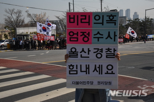 【울산=뉴시스】안정섭 기자 = 23일 오후 자유한국당 울산시당이 울산지방경찰청 앞에서 울산시장 측근이 연루된 아파트 공사비리 사건 수사 중단을 촉구하며 항의시위를 전개한 가운데 더불어민주당 관계자가 길 건너편에서 수사 지지 메시지를 담은 피켓을 들고 있다. 2018.03.23.  yohan@newsis.com