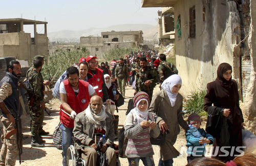 【동구타=AP/뉴시스】시리아 민간인들이 25일(현지시간) 정부군과 반군의 전투가 벌어지고 있는 동구타에서 빠져나오고 있다. 사진은 SANA통신 제공. .2018.3.26.