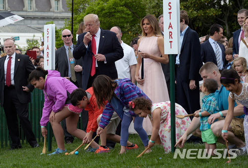 【워싱턴=AP/뉴시스】지난해 4월17일 도널드 트럼프 미 대통령이 백악관 사우스론에서 부인 멜라니아 여사가 지켜보는 가운데 백악관의 연례 부활절 달걀 굴리기 대회 시작을 알리는 호루라기를 불고 있다. 대통령 부부는 2일 약 3만명의 어른과 어린이들이 참여하는 가운데 백악관 부활절 달걀 굴리기 대회를 개최한다. 2018.4.2