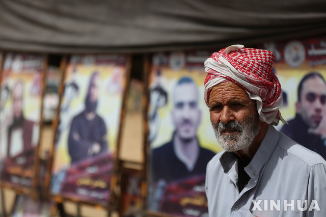 【 가자시티= 신화/뉴시스】 매주 금요일마다 열리는 가자지구 이스라엘 국경부근의 이스라엘 수감자 석방을 위한 집회에서 지난 4월 팔레스타인 남성 한 명이 수감자들 사진 앞에 서 있다. 2018.08.01