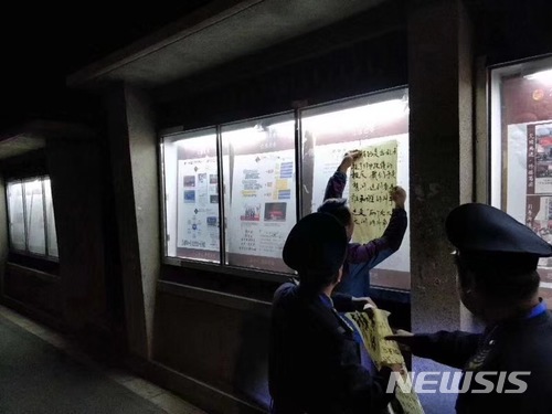 【서울=뉴시스】중국 베이징 대학측이 20여년 전 이 대학에서 발생한 성폭행 및 피해 여학생의 자살에 대한 진상 규명을 요구하는 여학생에게 침묵을 강요하는 위협을 한 것을 비난하는 대자보를 떼어내고 있다. <사진 출처 : supchina.com> 2018.4.25