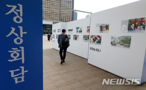 【서울=뉴시스】배훈식 기자 = 2018 남북 정상회담을 하루 앞둔 26일 오후 서울 중구 서울광장에 마련된 남북 정상회담 기록전 부스에서 한 시민이 김대중, 노무현 전 대통령의 정상회담 모습을 보고 있다. 2018.04.26. dahora83@newsis.com