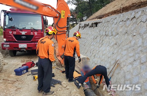【부산=뉴시스】 하경민 기자 = 27일 오후 5시께 부산 기장군의 한 도로공사 현장에서 옹벽에 균열이 생기면서 일부가 무너지는 바람에 옹벽 앞에서 배수관 설치 작업을 하던 인부 A(56)씨의 양쪽 다리가 배수관에 끼었다.신고를 받고 출동한 119구조대는 옹벽의 추가 붕괴를 막기 위해 굴착기가 받치고 있는 상황에서 에어백 등 장비를 사용해 약 1시간 만에 A씨를 구조해 인근 병원으로 옮겼다.2018.04.28. (사진=부산소방본부 제공)yulnetphoto@newsis.com