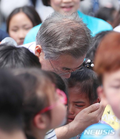 【서울=뉴시스】전신 기자 = 문재인 대통령이 지난해 5월 5일 청와대 녹지원에서 박 터뜨리기 도중 울고 있는 한 아이를 달래고 있다. 2018.05.05. photo1006@newsis.com