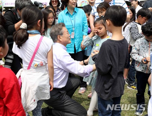 【서울=뉴시스】전신 기자 = 문재인 대통령이 지난해 5월 5일 청와대 녹지원에서 박 터뜨리기 도중 울고 있는 한 아이를 달래고 있다. 2018.05.05. photo1006@newsis.com