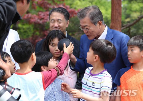 【서울=뉴시스】전신 기자 = 문재인 대통령이 지난해 5월 5일 청와대 녹지원에서 열린 2018 어린이날 청와대 초청행사에서 한 아이로부터 풍선을 선물받고 있다. 2018.05.05. photo1006@newsis.com