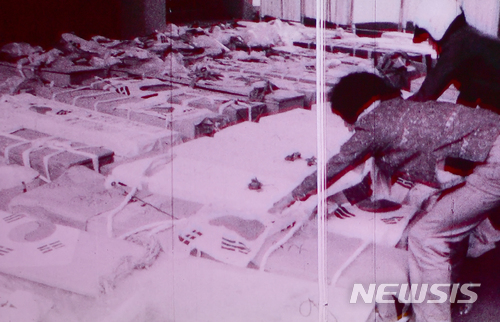 【광주=뉴시스】류형근 기자 = 1980년 5·18민주화운동 당시 계엄군의 잔혹함과 시민들의 분노, 항쟁이 끝난 뒤 광주 모습이 담긴 영상이 38년만인 9일 오후 광주 동구 국립아시아문화전당 극장3에서 처음 공개됐다. 희생자가 잠들어 있는 관 위에 태극기가 덮여 있다. 2018.05.09. (사진=5·18민주화운동기록관 공개 영상 촬영)&nbsp; photo@newsis.com